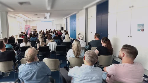 Personengruppe bei einer Veranstaltung, im Hintergrund ein Referent